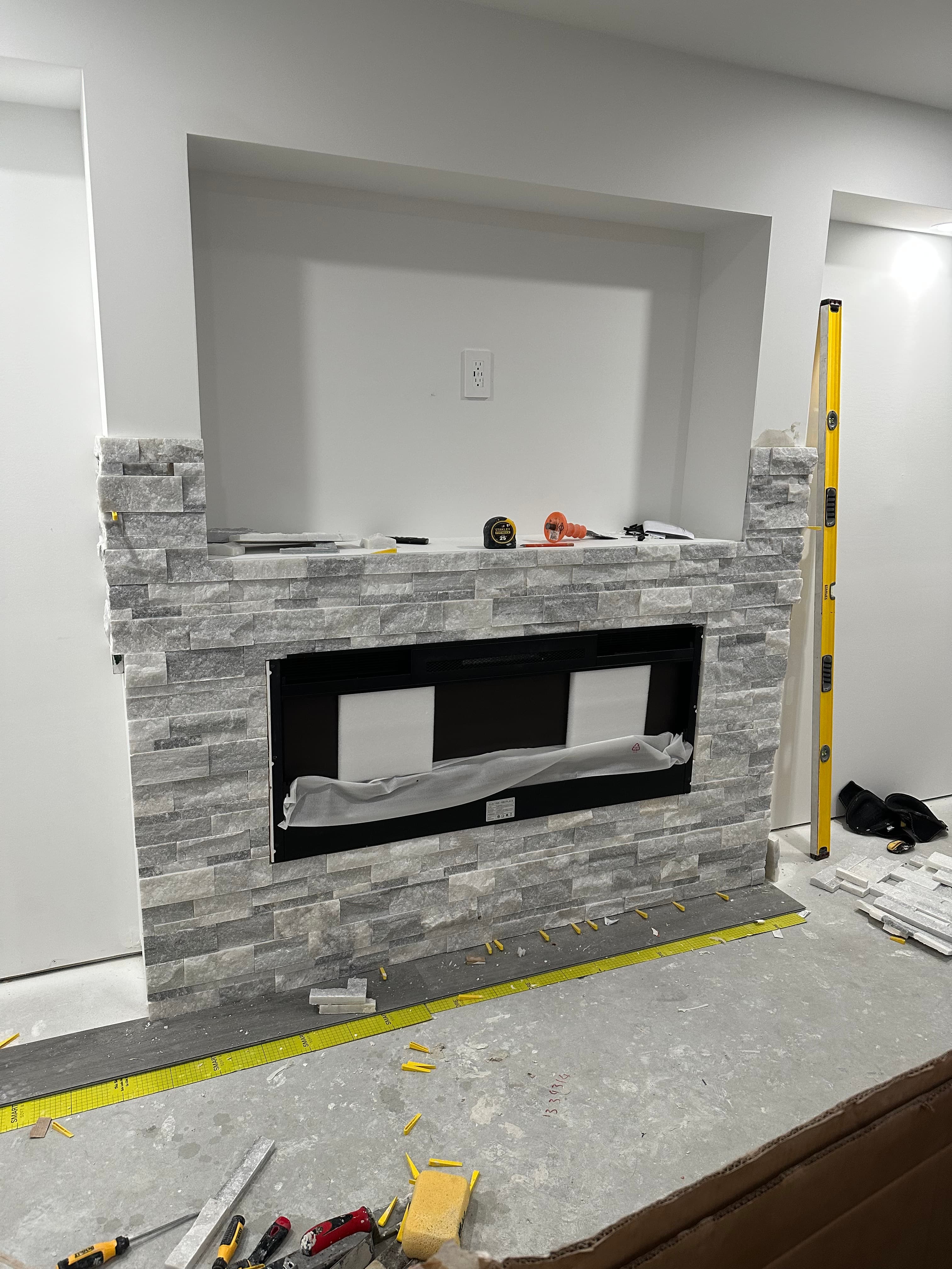 Grey stone veneer installation around a modern fireplace with a recessed wall niche above.